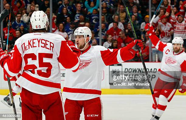 Henrik Zetterberg and Danny DeKeyser congratulate Tomas Tatar of the Detroit Red Wings who scored against the Vancouver Canucks during their NHL game...