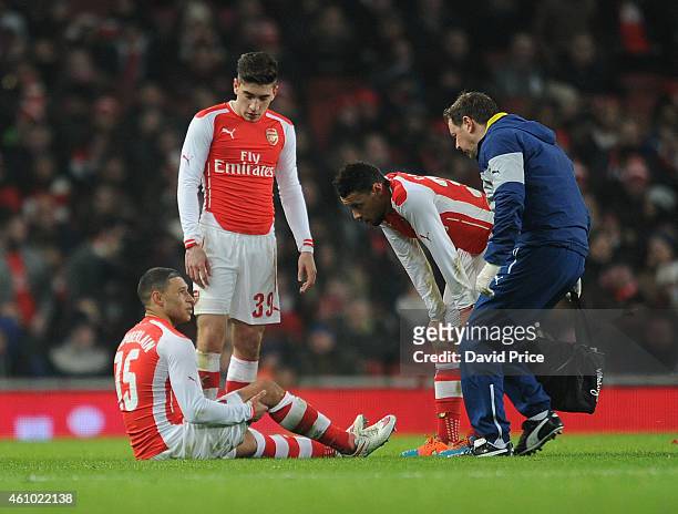 Alex Oxlade-Chamberlain of Arsenal speaks to Arsenal Physio Colin Lewin as Hector Bellerin and Francis Coquelin look on during the match between...