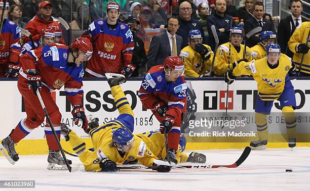 GTORONTO - JANUARY 4 - Sweden's Sebastian Aho falls over his teammate as both teams chase a loose puck in the neutral zone. 2015 IIHF World Junior...