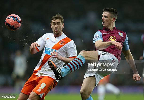 Ciaron Clark of Aston Villa clears the ball under pressure from Steve Davies of Blackpool during the FA Cup Third Round Match between Aston Villa and...