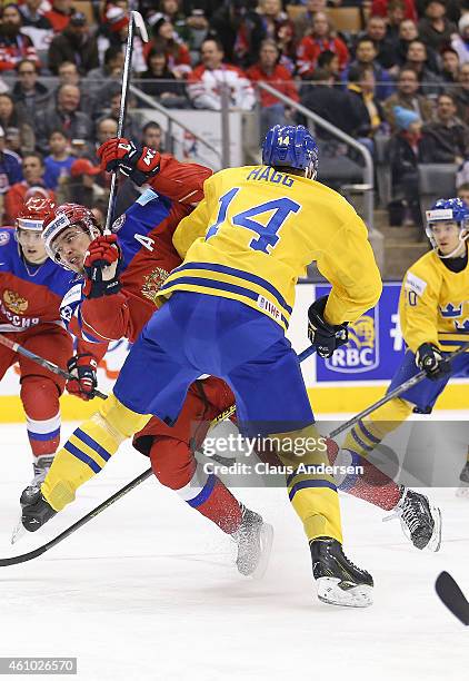 Pavel Buchnevich of Team Russia is slammed hard by Robert Hagg of Team Sweden during a semi-final game in the IIHF World Junior Hockey Championship...