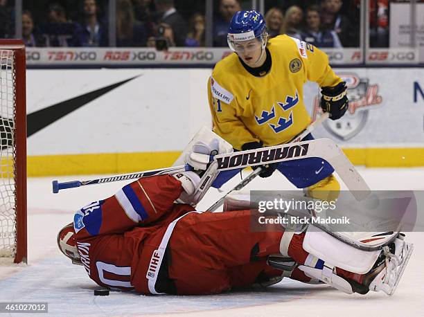 Sweden's William Nylander is hoping the puck will pop out but Russian goalie Igor Shestyorkin smothers the play by rolling onto the puck. 2015 IIHF...