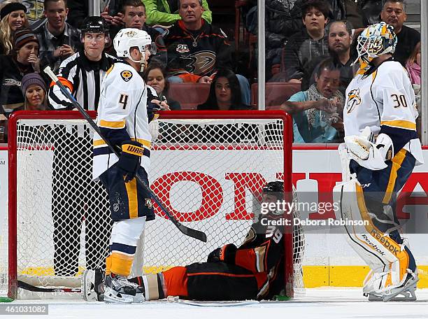 Ryan Ellis and Carter Hutton of the Nashville Predators talk as Matt Beleskey of the Anaheim Ducks looks on while sitting inside the net on January...