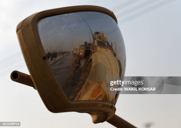 Soldiers are reflected in a rear view mirror at the scene with a damaged car following a suicide car bomb attack on a European Union police vehicle...