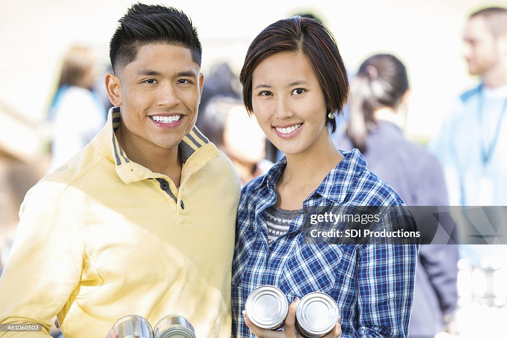 Friendly Asian couple volunteering together at donation food drive