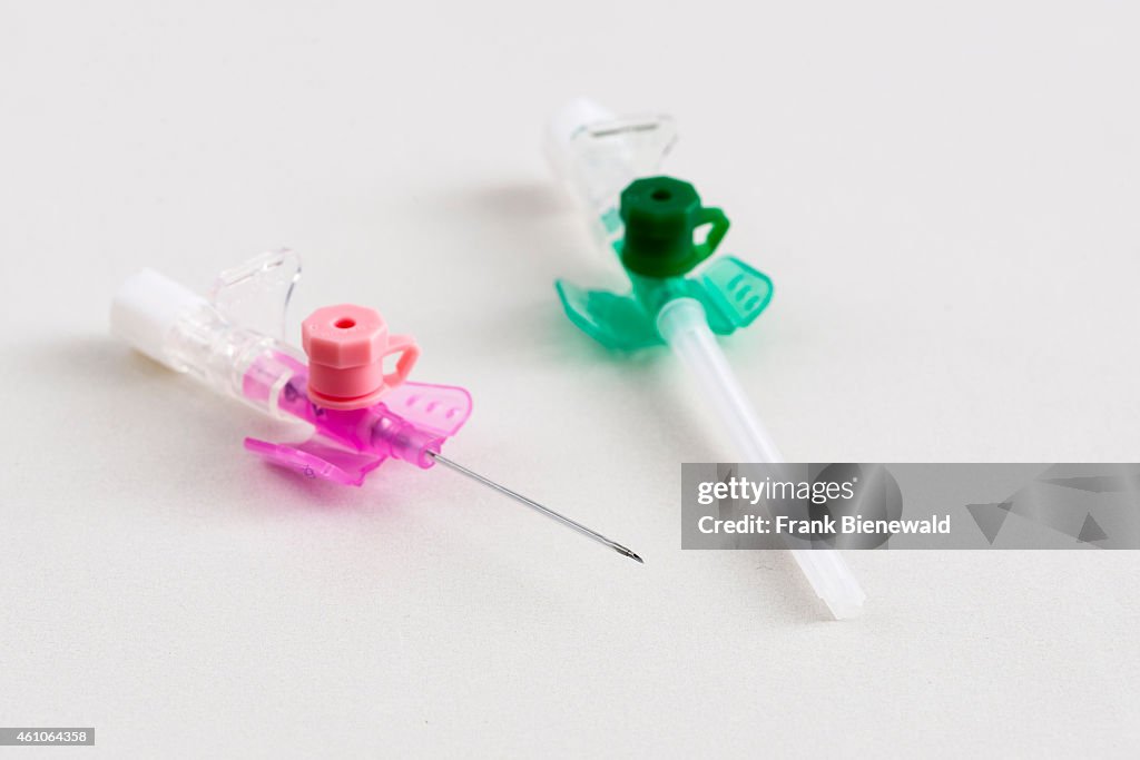 A pink an a green safety IV catheter with injection port for...