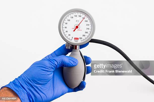 Hand in a blue medical glove is holding a sphygomanometer, blood pressure meter, for medical use, indicating high blood pressure, displayed on a...