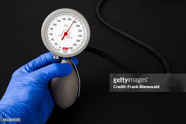 Hand in a blue medical glove is holding a sphygomanometer, blood pressure meter, for medical use, indicating high blood pressure, displayed on a...
