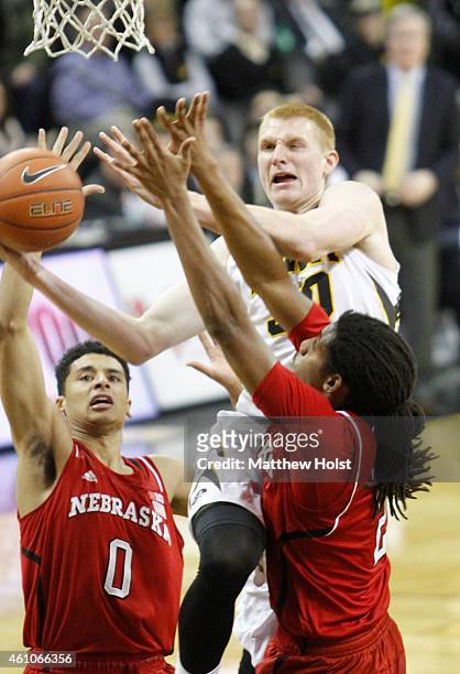 Forward Aaron White of the Iowa Hawkeyes drives to the basket against guard Tai Webster and forward David Rivers of the Nebraska Cornhuskers, in the...