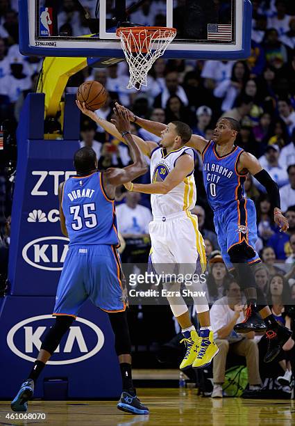 Stephen Curry of the Golden State Warriors goes up for a shot on Russell Westbrook and Kevin Durant of the Oklahoma City Thunder at ORACLE Arena on...