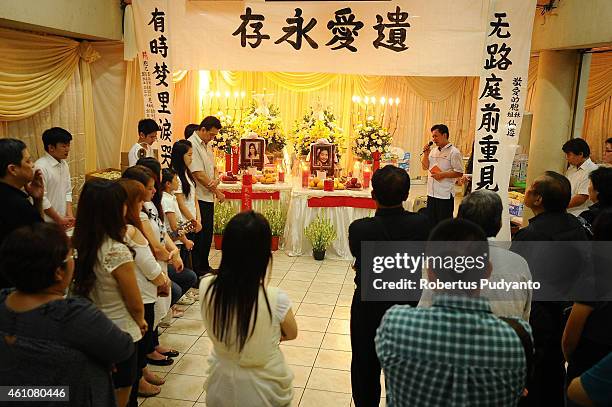 Relatives of The Meiji Tejakusuma and her daughter Jie Stevie Gunawan, victims of the AirAsia flight QZ8501 disaster pray together at Adi Yasa...