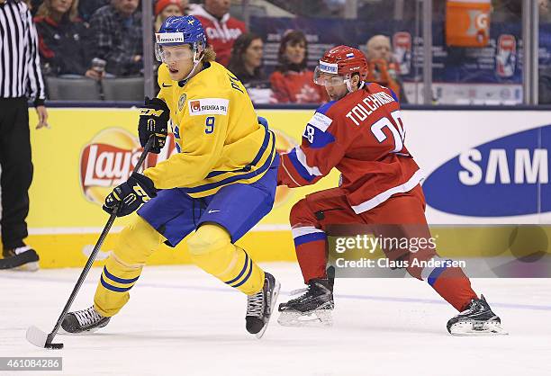 Sergei Tolchinski of Team Russia skates to check Jacob de la Rose of Team Sweden during a semi-final game in the 2015 IIHF World Junior Hockey...
