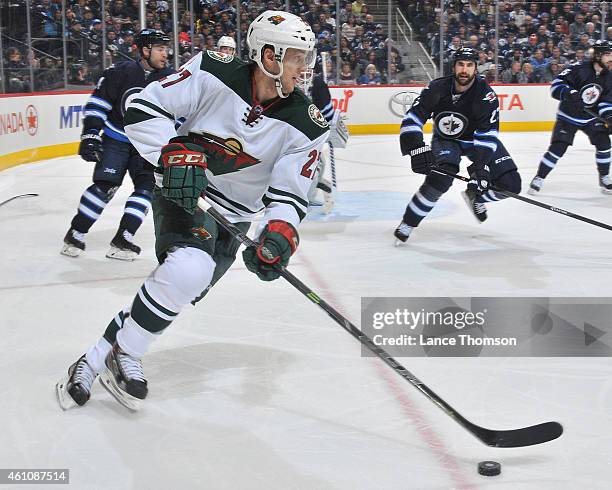 Brett Sutter of the Minnesota Wild plays the puck as Jay Harrison of the Winnipeg Jets defends during third period action on December 29, 2014 at the...