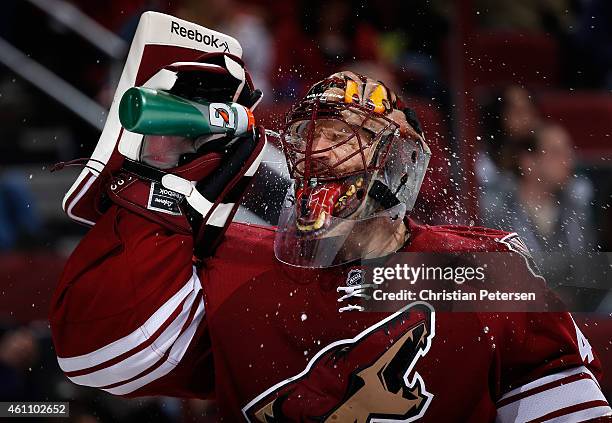 Goaltender Mike Smith of the Arizona Coyotes sprays water in his face during a break from the second period of the NHL game against the St. Louis...