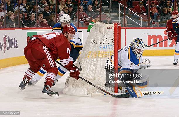 Goaltender Brian Elliott of the St Louis Blues makes a stick save as Joe Vitale of the Arizona Coyotes tries to wrap the puck around the post during...