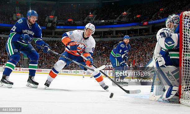 Alexander Edler of the Vancouver Canucks checks Mikhail Grabovski of the New York Islanders in front of Eddie Lack of the Canucks during their NHL...