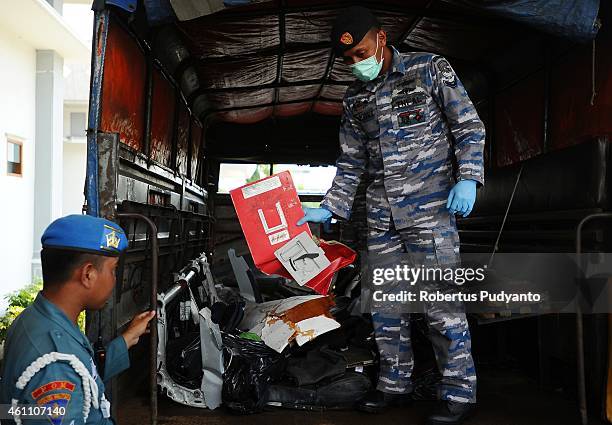 Indonesian Navy personnel show recovered parts of the aircraft AirAsia QZ8501 during a handover ceremony from Indonesian Navy to NTSC to continue...