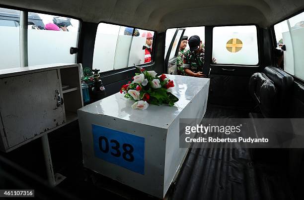 Indonesian Search and Rescue personnels place a coffin containing a victim of the AirAsia flight QZ8501 disaster in an ambulance to continue...
