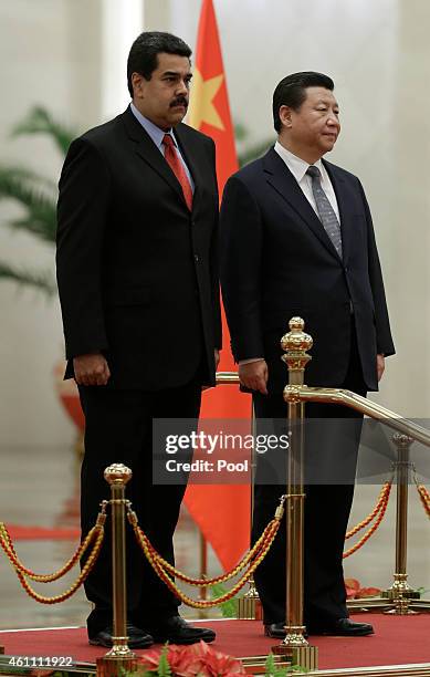 Venezuela's President Nicolas Maduro and Chinese President Xi Jinping stand on podium as they listen to the national anthems during a welcoming...