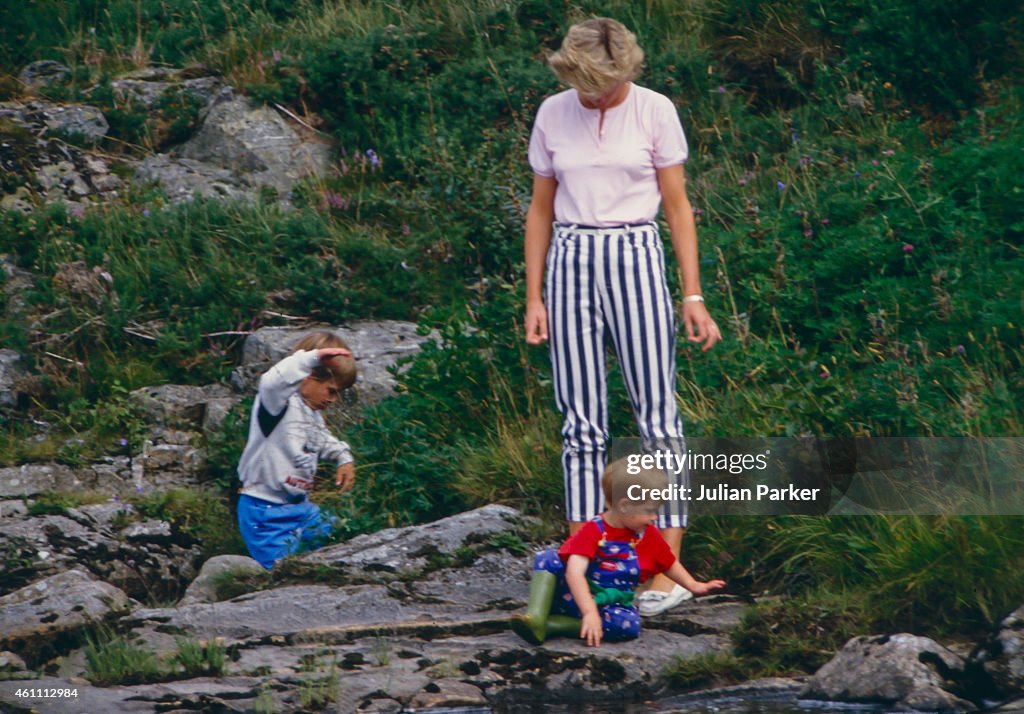 Diana, Princess of Wales, Prince William, and Prince Harry play on the banks of the River Dee, near Balmoral Castle