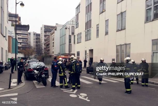 Police officers and firefighters gather in front of the offices of the French satirical newspaper Charlie Hebdo in Paris on January 7 after armed...