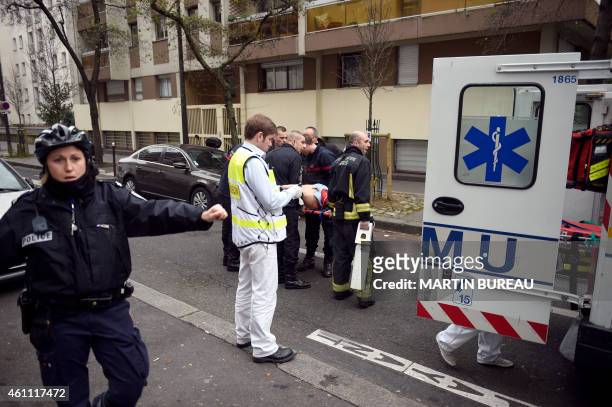 Firefighters carry an injured man on a stretcher in front of the offices of the French satirical newspaper Charlie Hebdo in Paris on January 7 after...
