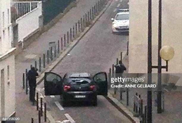 Armed gunmen face police officers near the offices of the French satirical newspaper Charlie Hebdo in Paris on January 7 during an attack on the...
