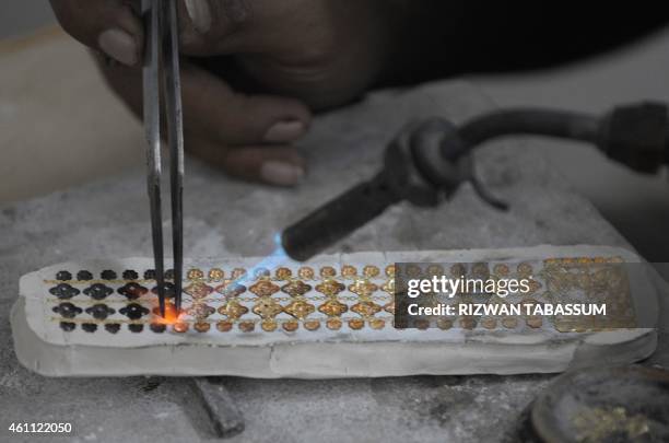Pakistani jeweller prepares pieces for a necklace at his gold workshop in Karachi on January 7, 2015. The International Monetary Fund announced...