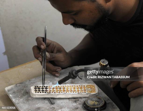 Pakistani jeweller prepares pieces for a necklace at his gold workshop in Karachi on January 7, 2015. The International Monetary Fund announced...