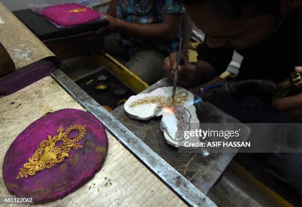 Pakistani jeweller makes a necklace at his gold workshop in Karachi on January 7, 2015. The International Monetary Fund announced December 2014 that...