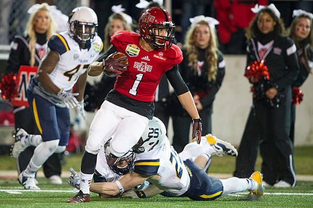 Defensive back Blaise Taylor of the Arkansas State Red Wolves attempts to escape a tackle by wide receiver Cody Thompson of the Toledo Rockets during...
