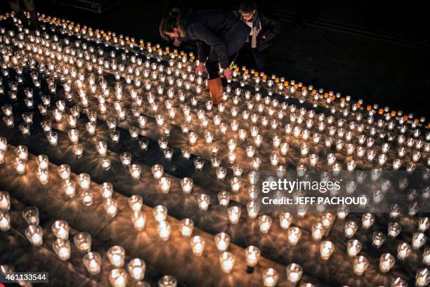 Woman lights a candle during a gathering in Lyon, central eastern France, on January 7 following an attack by unknown gunmen on the offices of the...