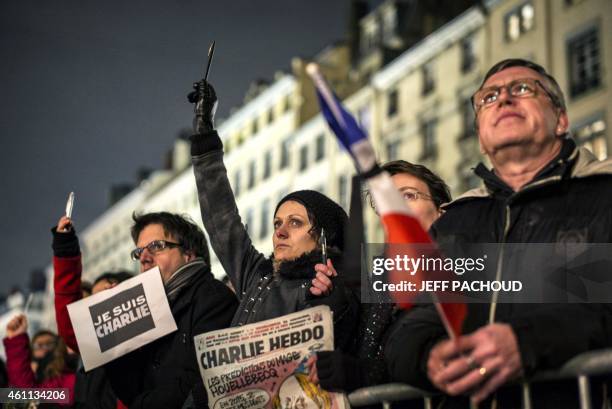 Woman cries as she holds up a pen during a vigil in Lyon on January 7 following an attack by unknown gunmen on the offices of the satirical weekly,...