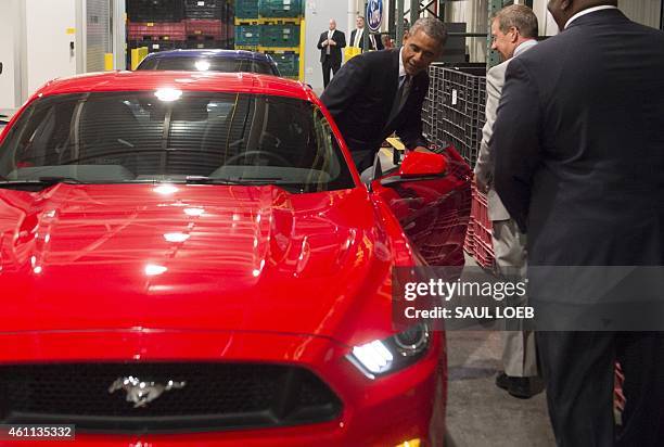 President Barack Obama opens the door to a Ford Mustang prior to speaking about the automotive manufacturing industry at the Ford Michigan Assembly...