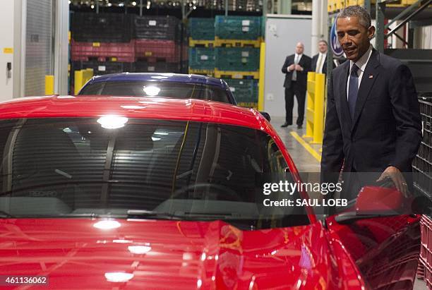 President Barack Obama opens the door to a Ford Mustang prior to speaking about the automotive manufacturing industry at the Ford Michigan Assembly...