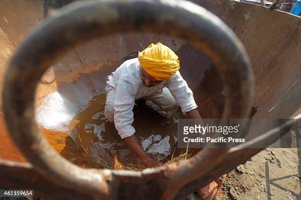 The man prepares a big pot to be used in cooking food for langar at a camp durin the one month "Magh Mela" festival.