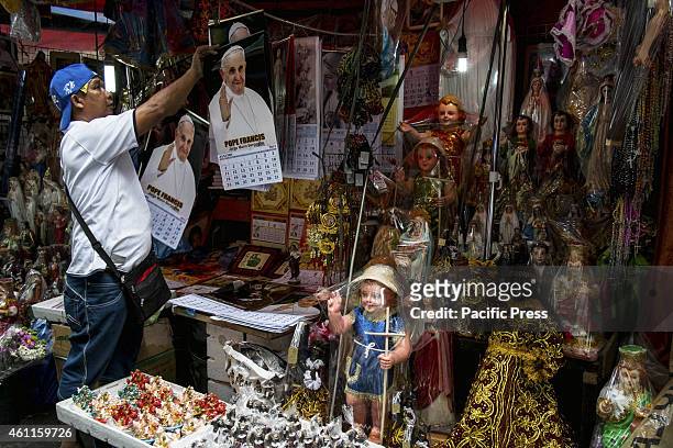 Jun Laxa, a 56 years old vendor in Quiapo hangs calendars with the image of Pope Francis.