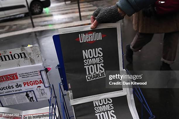 Woman buys a copy of 'Le Figaro' newspaper from a news kiosk with a front page story on yesterday's terrorist attack, on January 8, 2015 in Paris,...