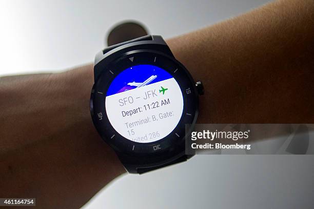 An exhibitor displays flight information on an LG G Watch R smartwatch, manufactured by LG Electronics Inc., during at the 2015 Consumer Electronics...
