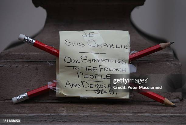 Pair of pencils and a note offering sympathy to the victims of the Paris shootings are placed on a wall at the French Embassy on January 8, 2015 in...