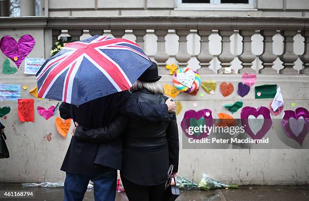 Man who had just placed a pair of pencils and a note offering sympathy to the victims of the Paris shootings on a wall at the French Embassy stands...