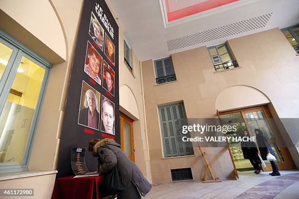 Woman signs a condolence book near a banner reading "Je suis Charlie" featuring the portraits of late Charlie Hebdo editor Stephane Charbonnier ,...