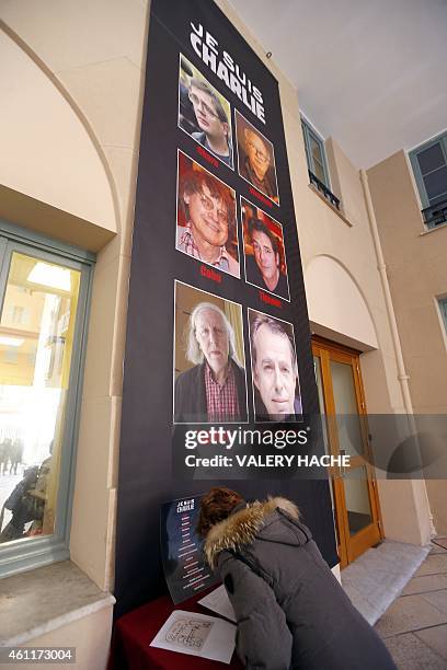 Woman signs a condolence book near a banner reading "Je suis Charlie" featuring the portraits of late Charlie Hebdo editor Stephane Charbonnier ,...