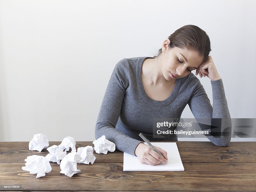 Woman writing on paper with crumpled paper