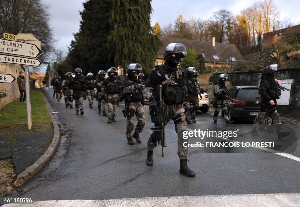 Members of the GIPN and RAID, French police special forces, walk in Corcy, northern France, on January 8, 2015 as they carry out searches as part of...