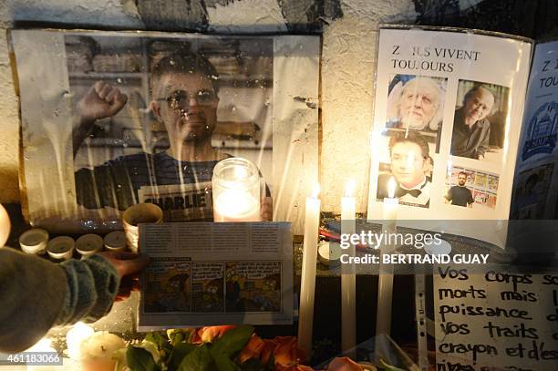 Candles are lit next to pictures of late French cartoonists Cabu, Charb, Tignous and Honore during a rally at Republic Square in Paris on January 8 a...