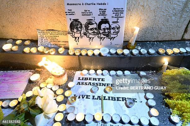 Candles are placed around a cartoon depicting late French cartoonists Cabu, Charb, Tignous and Wolinski during a rally at Republic Square in Paris on...