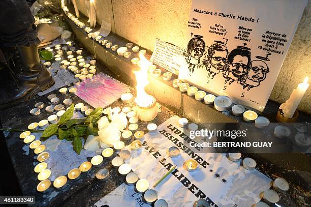 Candles are lit around a cartoon depicting late French cartoonists Cabu, Charb, Tignous and Wolinski during a rally at Republic Square in Paris on...