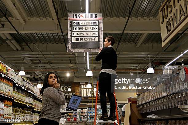 Natasha Jain, left, of Haverhill, looks back down the aisle as Meghann Brideau, of Roslindale, puts up signage at the new Whole Foods Market in South...
