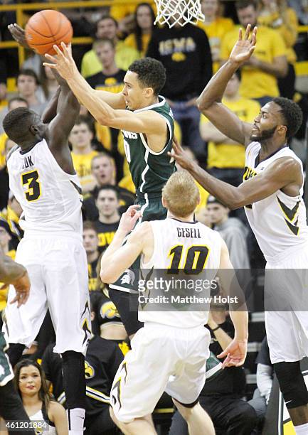Guard Travis Trice of the Michigan State Spartans drives to the basket against guard Peter Jok, guard Mike Gesell and center Gabriel Olaseni of the...